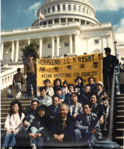 Photo of multiple people sitting in DC and holding a banner that reads "Housing is a right! Asian Americans for Equality."