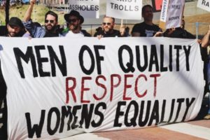 Photo of protesters holding a banner that reads "Men of quality respect women's equality."