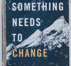 Book cover with white snow-capped mountains on blue background with the words "Something Needs to Change"