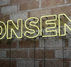 Glowing neon sign that reads "CONSENT" on a stonework wall.
