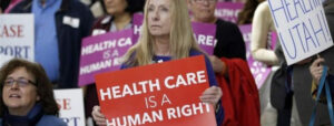 Image of group of protesters, one of whom is holding a sign that reads "Health care is a human right."