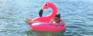 Photo of Laura Chow Reeve of the Action Alliance laying on a flamingo shaped inner tube in a body of water.