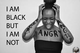 Black and white photo of a Black woman with her mouth open and hands held up to her head. Text on the left reads "I am black but I am not" and then the word "Angry" is painted on her body multiple times.