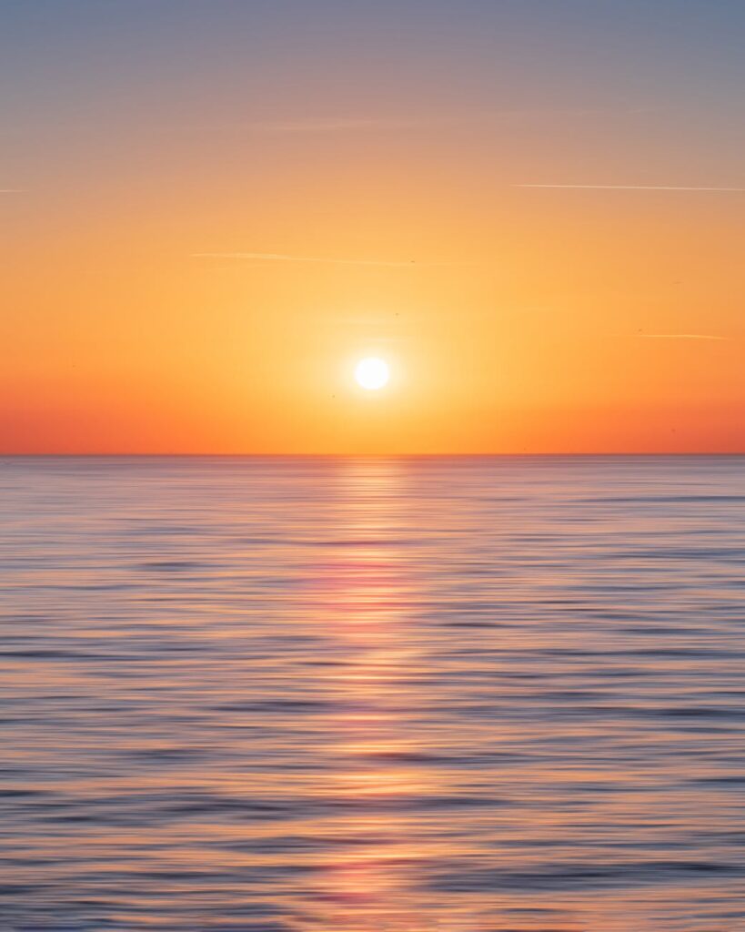 calm water with sun and orange sky