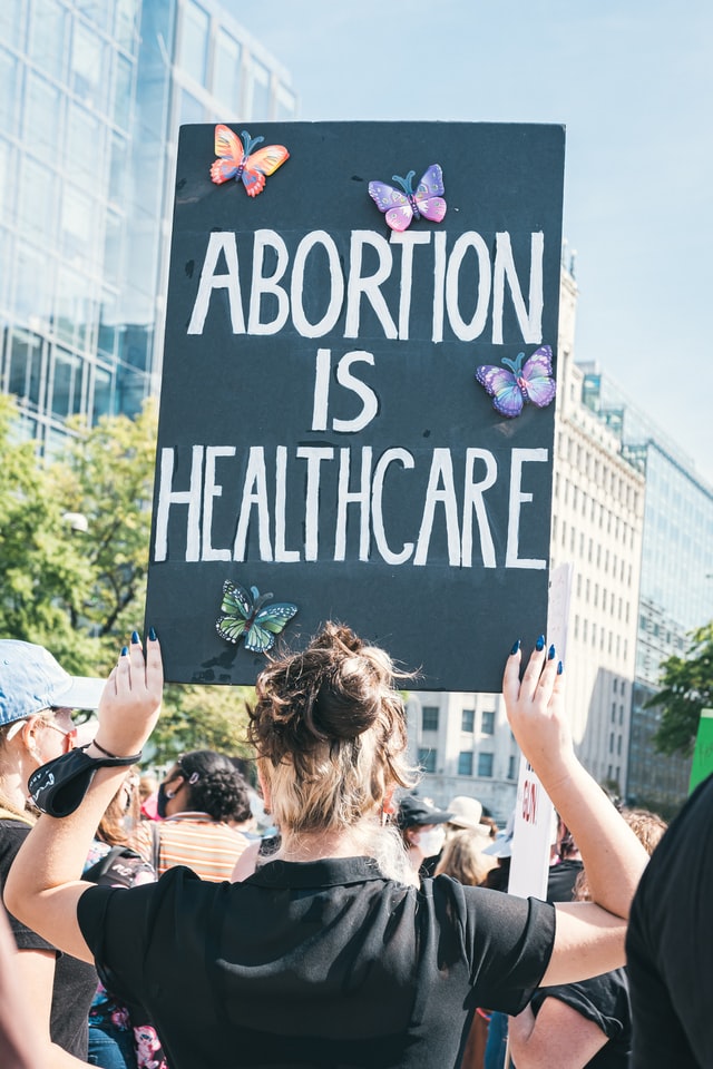 A woman holding up a protest sign that reads Abortion is Healthcare.